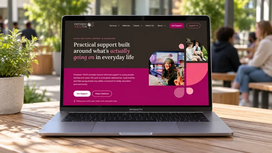 The Empower YOUth home page on a laptop, on a wooden table outdoors.